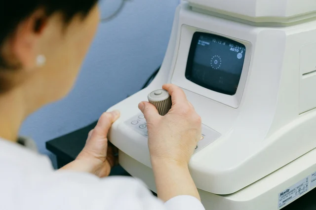 An optometrist conducts an eye examination using a slit lamp at an eye clinic