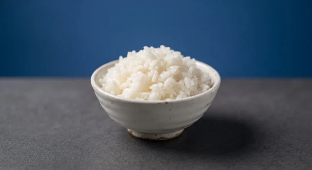 A ceramic bowl filled with freshly steamed, fluffy white rice on a clean table