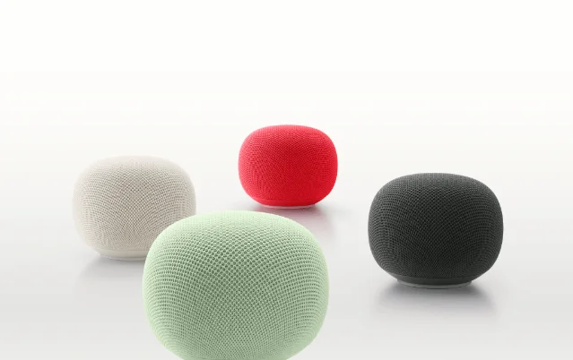 Four Google Home smart speakers in white, red, green and dark grey mesh