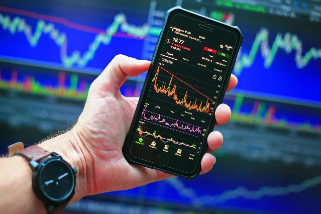 Stock market chart and smartphone showing investment data