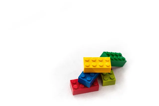 Colorful LEGO bricks in red, blue, yellow, and green scattered on a white studio surface — illustrating typical LEGO Icons set piece variety