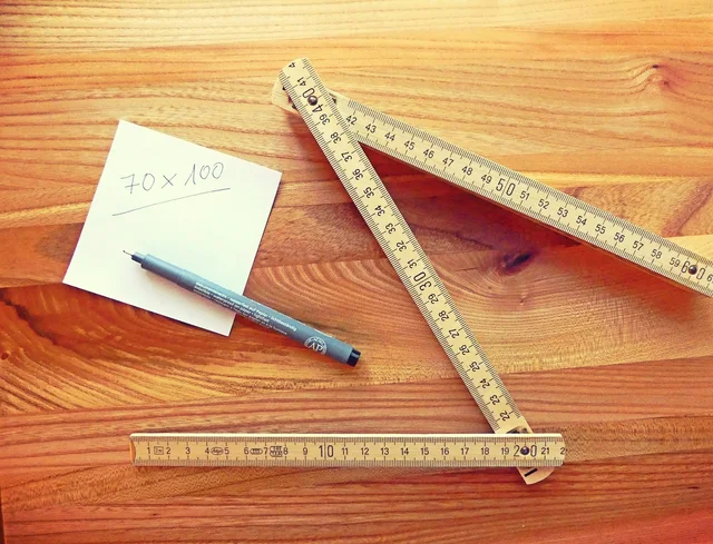 A folding rule, a steel ruler and a written note of dimensions on a wooden board
