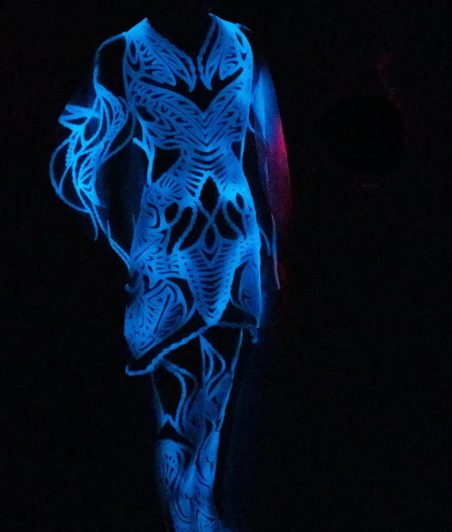 Iris van Herpen, The Living Look, a gown glowing blue in a black space, worn during the Sympoiesis couture show in Paris, July 2025