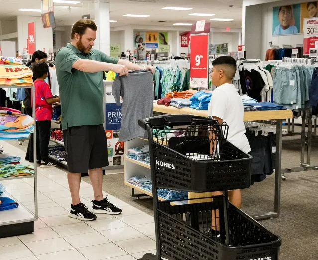 A volunteer helps a child choose a shirt during the Clubs' 2025 back-to-school shopping event.