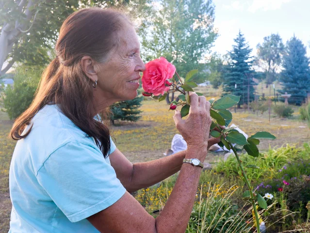 Cindy Wilson, 69, holds a rose up to her face in her garden in Doney Park, Arizona