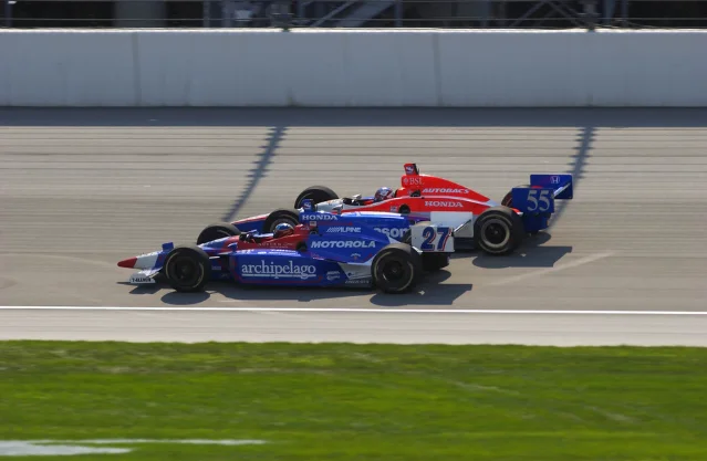 Two open-wheel race cars run close together on a track.