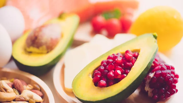 Healthy omega-3 food sources including salmon, eggs, avocado, nuts and fresh vegetables on a white surface