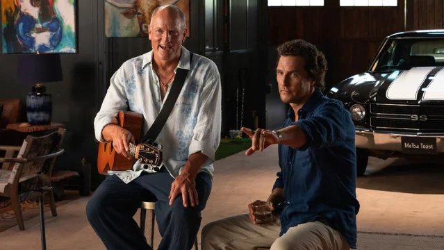 Woody Harrelson with a guitar sitting beside Matthew McConaughey on a ranch set in Brothers