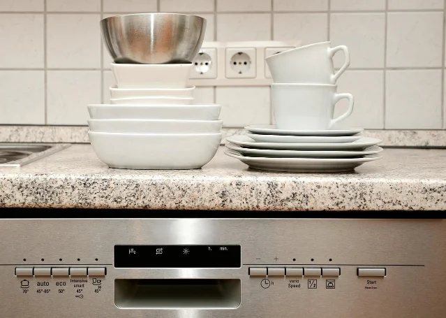Stacked dishes waiting above a dishwasher