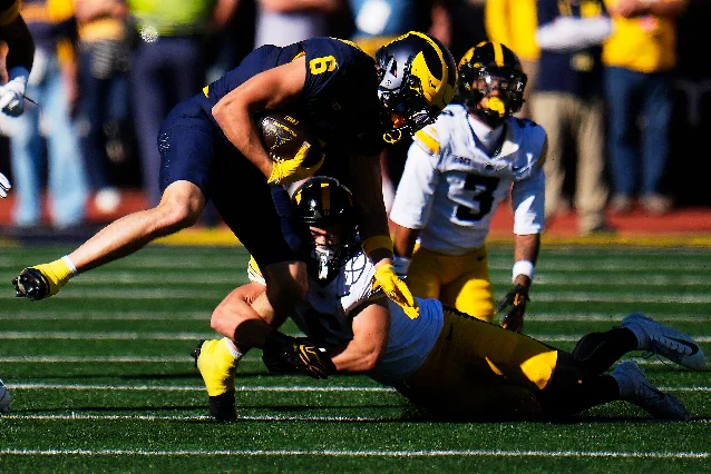 Michigan receiver JJ Buchanan is tackled by Iowa defensive back Zach Lutmer in Ann Arbor