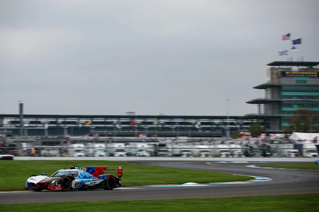 The No. 24 BMW M Hybrid V8 prototype racing past a grandstand at Indianapolis Motor Speedway