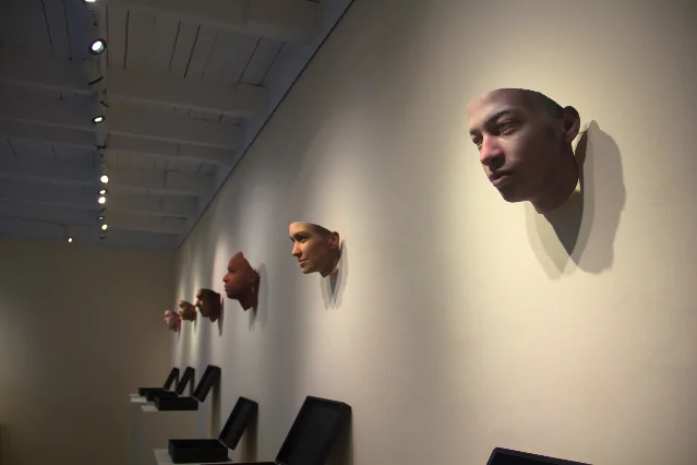 A gallery wall of 3D-printed faces above open evidence boxes