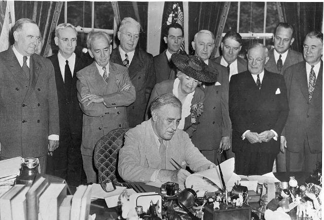FDR signing the GI Bill on June 22, 1944, surrounded by congressional representatives and American Legion officials including John H. Stelle and Harry Colmery