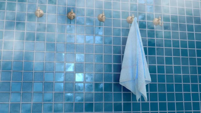 A white towel hanging open against blue bathroom tiles