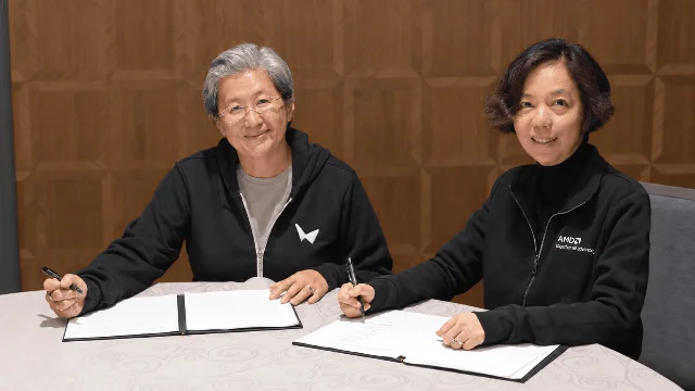 Fei-Fei Li and Lisa Su sitting at a table signing documents