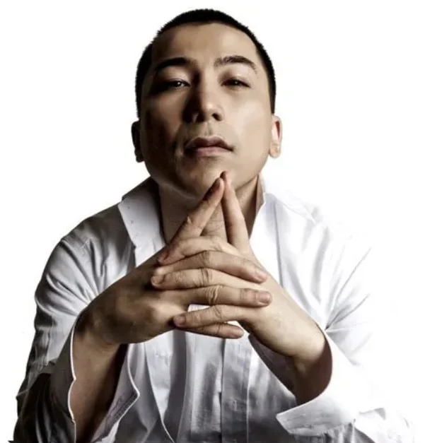 一位短发男子双手交叠抵在下巴前的正面肖像照
