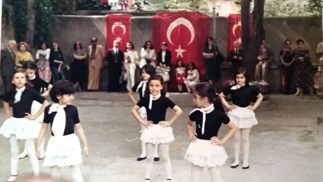 Young dancers including Berna Akinal perform a routine on an outdoor stage in Istanbul, flanked by Turkish flags.