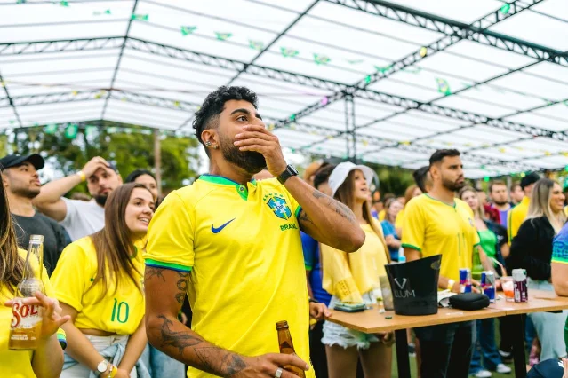 Brazilian football fans in yellow jerseys watching a match with emotion