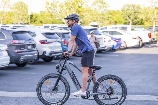 Rider on a commuter electric bike in an urban setting, wearing a helmet