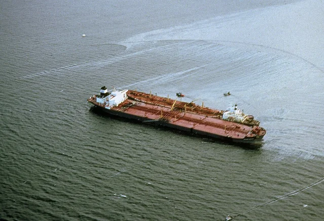 Aerial view of the Exxon Valdez grounded in Prince William Sound, surrounded by spreading oil slick and response vessels