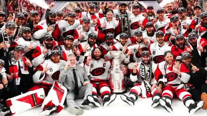 Carolina Hurricanes players in championship gear celebrating with the Stanley Cup on T-Mobile Arena ice after Game 6
