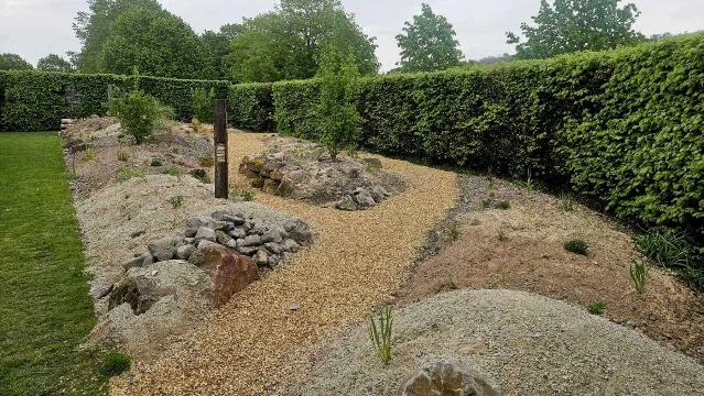 A finished gravel and xerophytic garden with stone mounds and a winding path.