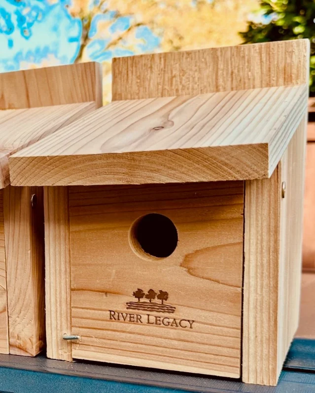 A wooden birdhouse stamped with the River Legacy logo