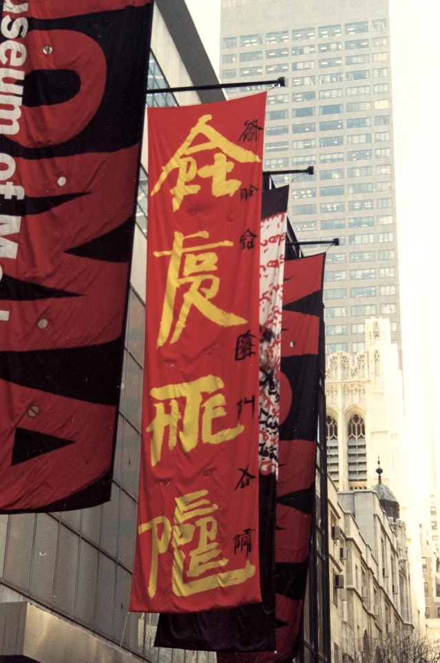 纽约街头,多面红黑白三色的竖幅从建筑外墙面垂下,其中一面写着金色大字