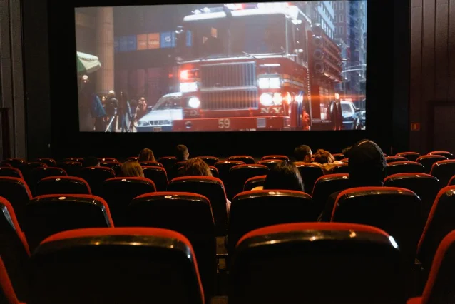 People seated in a cinema watching a movie on a large screen.