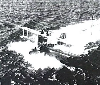 A Supermarine Seagull III amphibious biplane trailing a wake on the sea