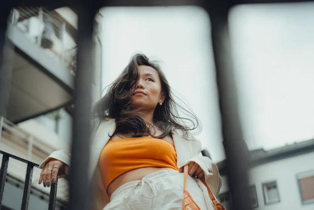 Woman in orange crop top and white blazer, urban street setting