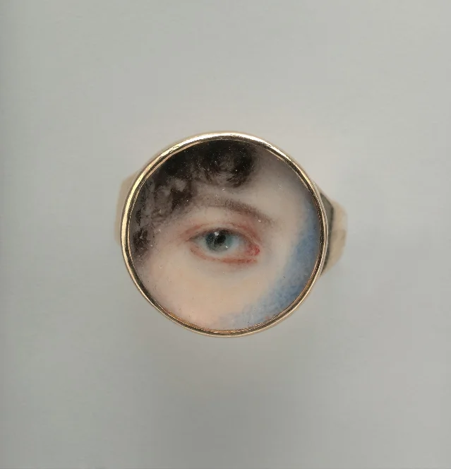 A gold ring set with a painted blue eye framed in a circle of enamel