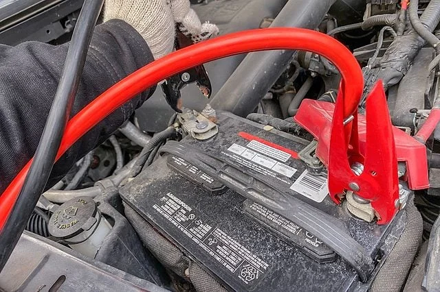 Red and black jumper cables attached in an engine bay