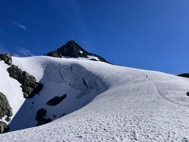 Mount Shuksan's summit pyramid rising above glacier snow on a late-July climbing route.