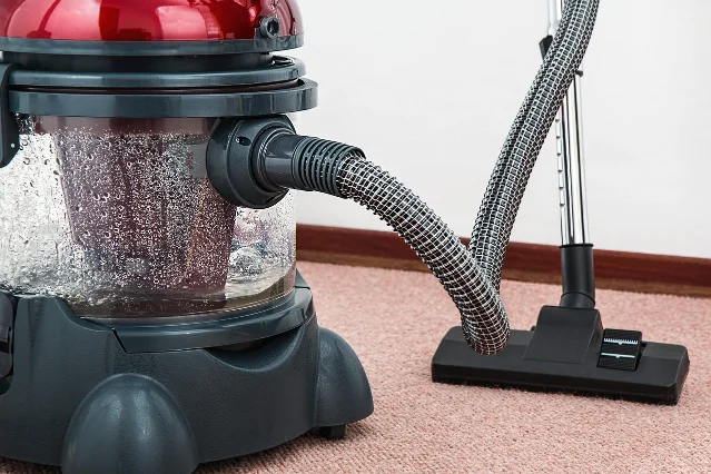 A vacuum cleaner on a carpeted living room floor with natural light
