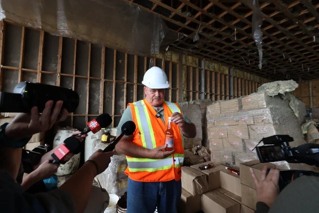 Glenn Sharp holds a bottle of fish sauce inside the abandoned plant in St. Mary's.