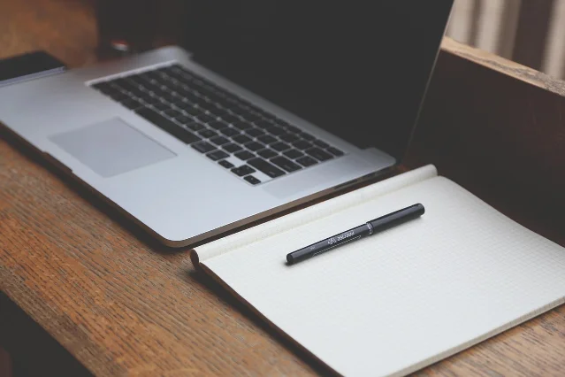 Typing on a laptop beside a notebook