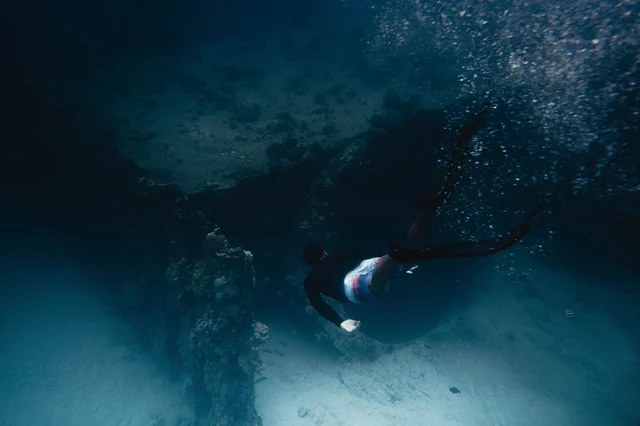 A scuba diver swimming through a vivid coral reef underwater