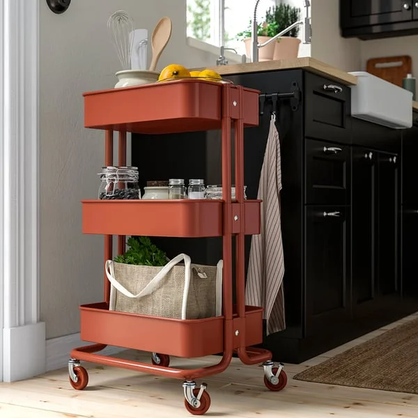 Red-brown RÅSKOG trolley beside a compact kitchen