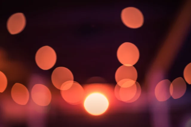 Warm-toned circular bokeh orbs against a dark background, demonstrating the creamy smooth bokeh aesthetic