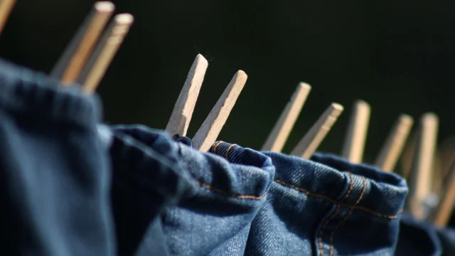 Jeans drying on a clothesline with wooden clothespins