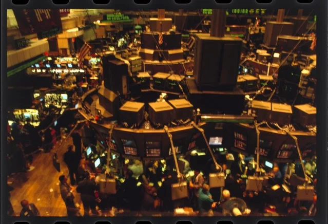 A crowded stock exchange trading floor with desks and monitors