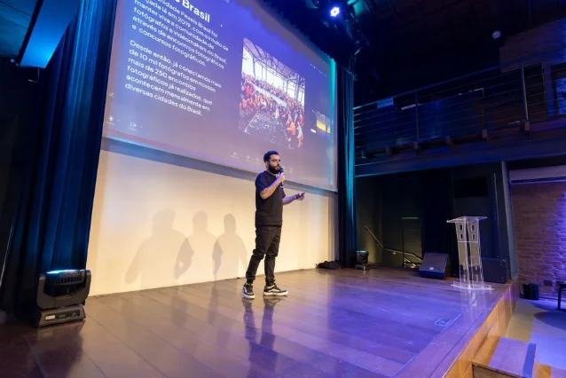 Speaker presenting at a modern tech conference with projected slides on screen