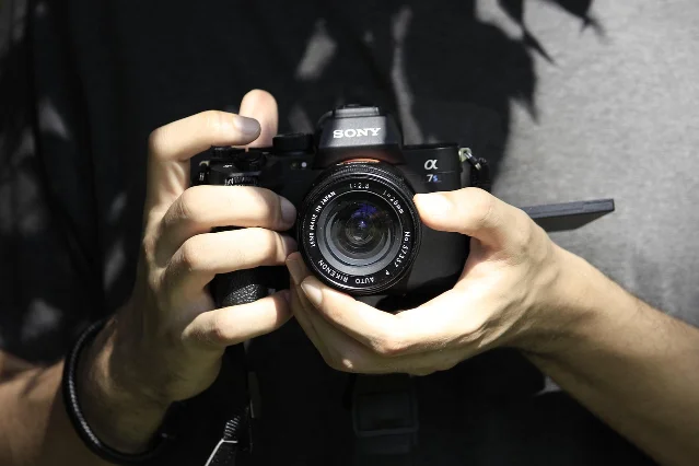 Sony A7 mirrorless camera body with vintage 28mm lens, held in hands