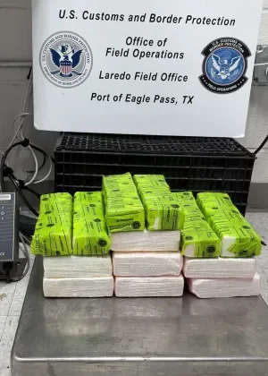 Thirteen lime-green wrapped cocaine packages arranged on a stainless steel inspection table, with a CBP "Port of Eagle Pass, TX" sign in the background