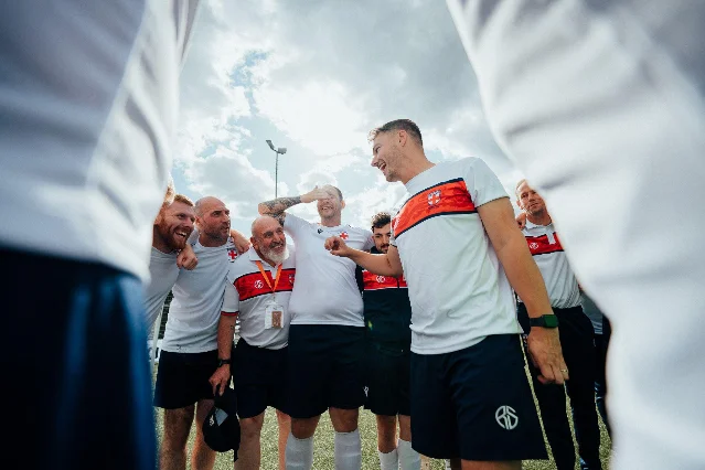 England's players and staff coming together in a huddle after the final