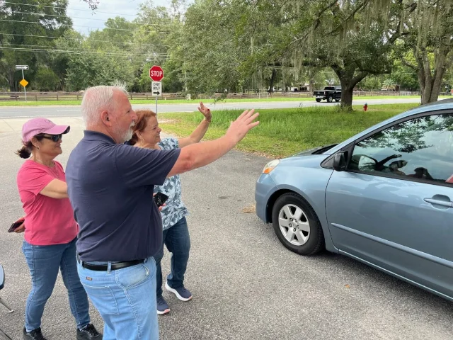 Church volunteers wave as a car leaves the Niagara Cares distribution event in Ocala.