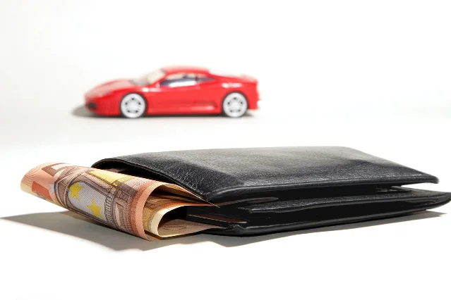A car with financing documents and banknotes representing auto loan costs