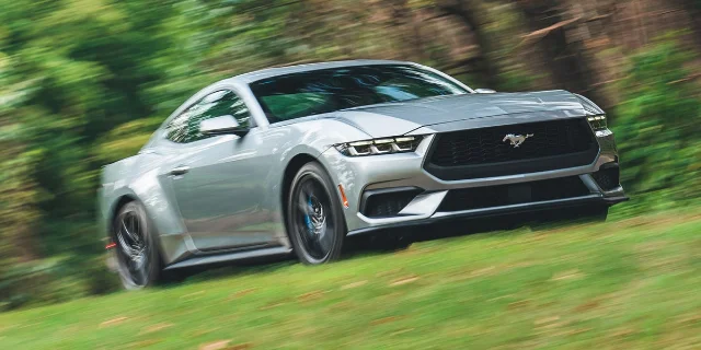Silver Ford Mustang EcoBoost moving across a grass field