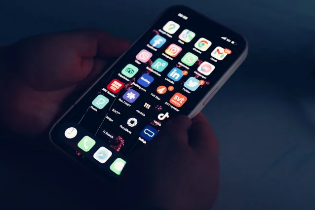 用户手持手机浏览新闻 App 界面,屏幕可见多个资讯类应用图标